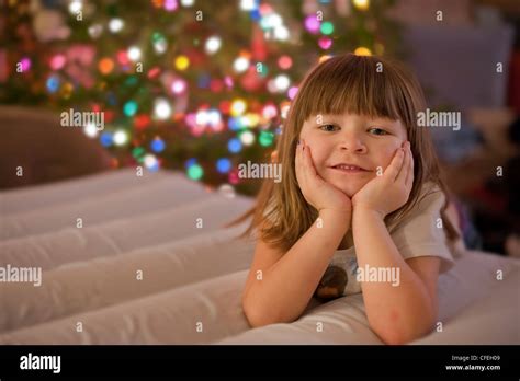 Cute 5 Year Old Girl Posing In Front Of A Colorful Christmas Tree And