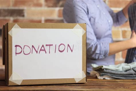 Volunteer Is Puting Clothes To Cardboard Box For Donation Stock Photo