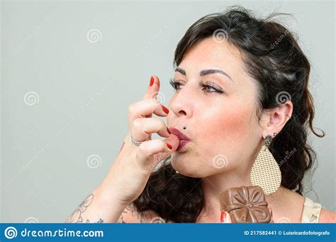 Closeup Of Tattooed Woman Licking Her Fingers And Holding A Brazilian