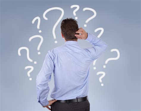 Confused Businessman Standing In Front Of A Wall Of Question Mar Coachme