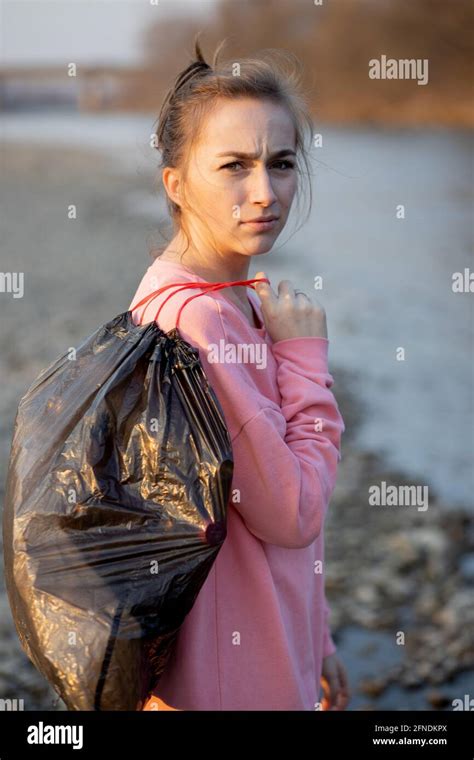 woman picking up trash and plastics cleaning the beach with a garbage bag environmental