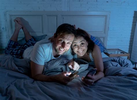 Couple On Mobile Phones In Bed Late At Night Enjoying Social Network Games And Internet