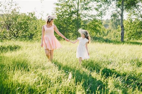 Mom And Daughter Walking On The Field In The Summer Sunny Day At Sunset