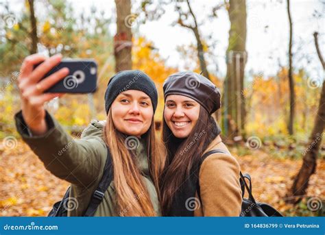 Two Pretty Women Taking Selfie Picture On Phone Outdoors At Autumn City Park Stock Image Image