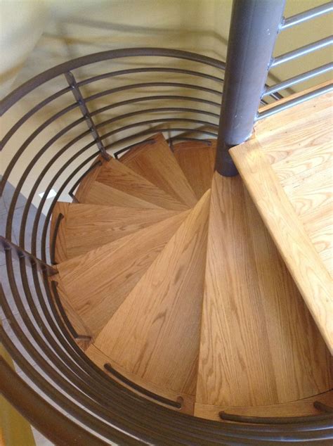 There Is A Spiral Wooden Staircase In The House With Metal Handrails