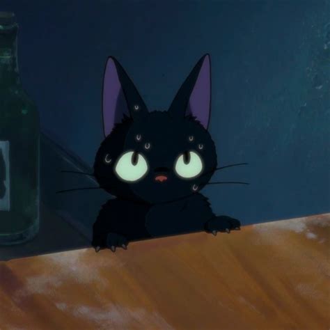 A Black Cat Sitting On Top Of A Wooden Table Next To A Green Glass Bottle