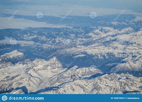 View Over The Clouds From The Porthole Of An Airplane Of Swiss Alps