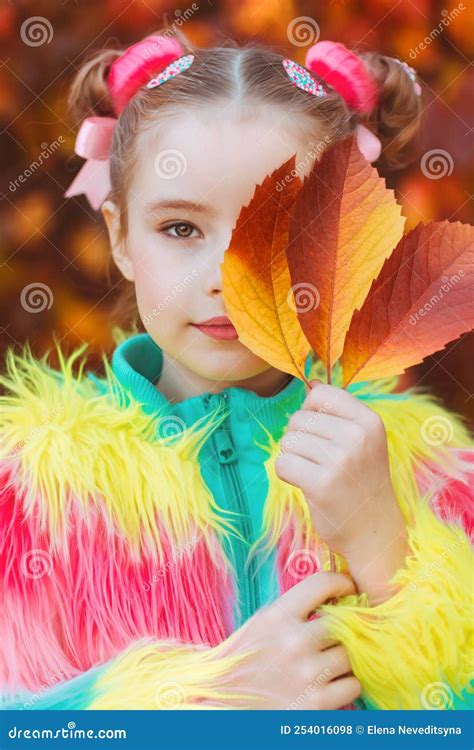 A Girl In Colored Clothes Covers Half Of Her Face With An Autumn Yellow