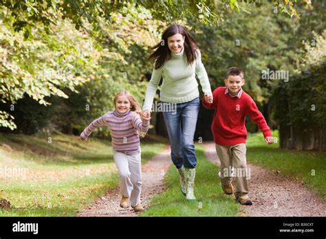 Woman Outdoors With Two Young Children Walking On Path Holding Hands