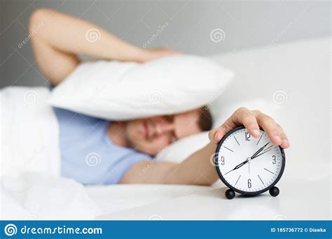Man Waking Up With Alarm Clock In Bedroom At Home Stock Photo Image