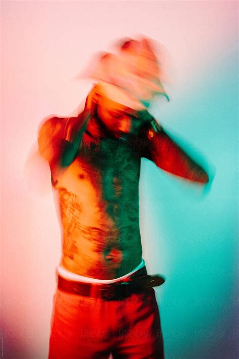 Bare Chested Heavily Tattooed Man Wearing A Yoruba Hat With Orange And Green Lighting By