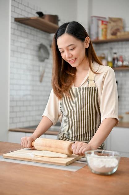 Premium Photo Happy Asian Female In Apron Is Kneading Raw Dough With