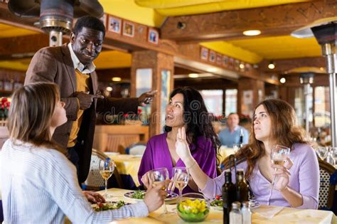 hombres sonrientes invitan a las mujeres a cenar en un restaurante foto de archivo imagen de