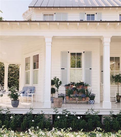 A White House With Potted Plants On The Front Porch