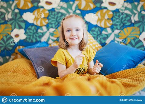 Adorable Little Girl Sitting On Bed In Nicely Decorated Bedroom Stock