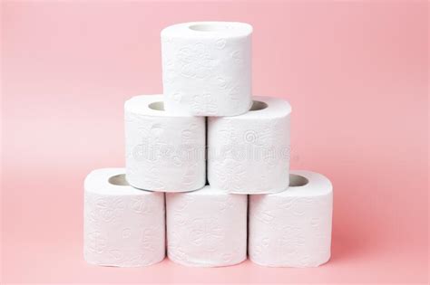 A Stack Of White Rolls In Toilet Paper On A Pink Background Close Up