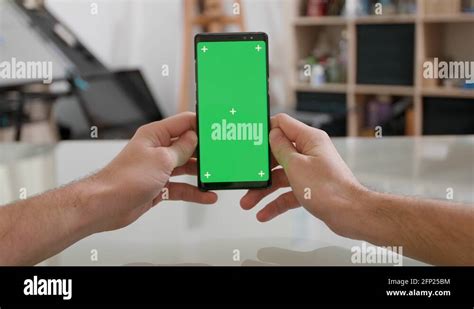 Mans Point Of View Holding A Smartphone Vertically With Green Screen On