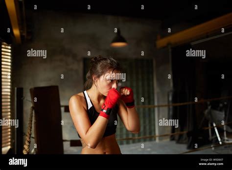 Dramatic Side View Portrait Of Tough Female Boxer Practicing In Boxing