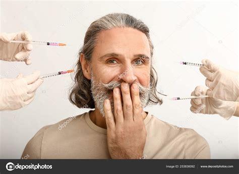 Mature Man And Hands Holding Syringes For Anti Aging Injections On White Background Stock Photo