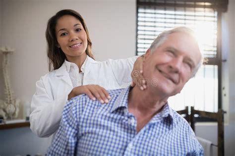 Portrait Of Smiling Female Therapist Giving Neck Massage To Senior
