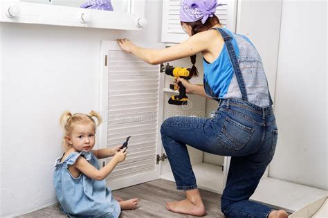 Mom Performs Men`s Work Mom And Daughter Hang The Door Of A White