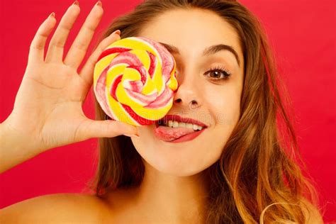 Portrait Of A Happy Pretty Girl Holding Sweet Candy Over Red Background
