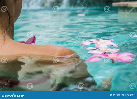 vrouw in een zwembad tropische bloemen frangipani plumeria leelawadee die in het water drijft