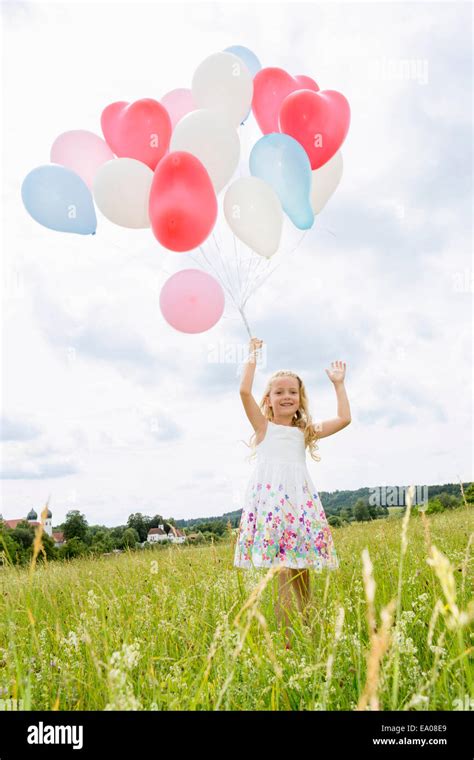 Girl Holding Balloons In Field Stock Photo Alamy