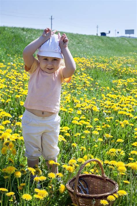 Little Caucasian Girl Playing In Green Grass Meadow In Yellow Flowers