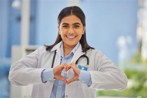Portrait Of A Happy Mixed Race Female Doctor Forming A Heart Shape With