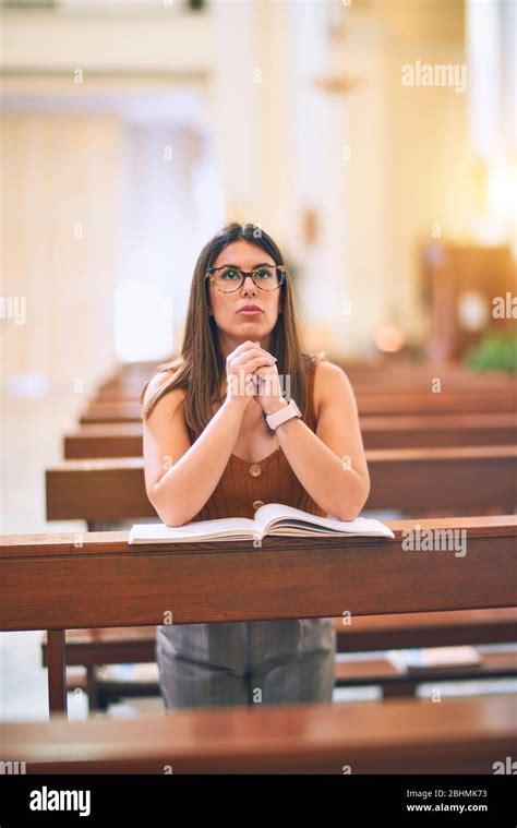 Joven Hermosa Mujer Orando De Rodillas En Un Banco De La Iglesia