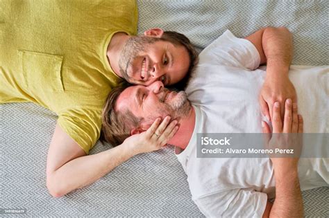 Picture From Above Of Real Gay Couple Smiling Lying In Bed On Their