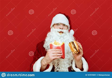 Portrait Of Funny Santa Claus Eating Fast Food On Red Background And