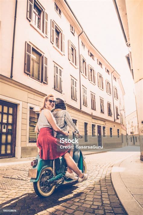 Young Lesbian Couple Driving Oldfashioned Motor Scooter On Italian City