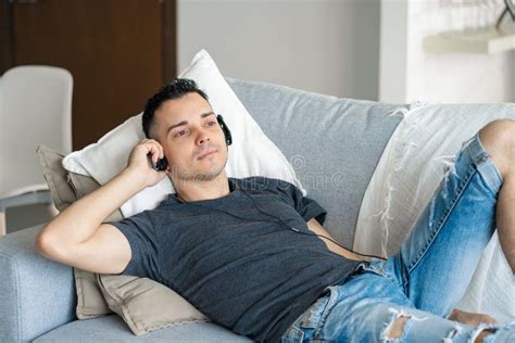 The Guy Enjoys The Music While Lying On The Couch With Headphones Relaxation With Music Stock