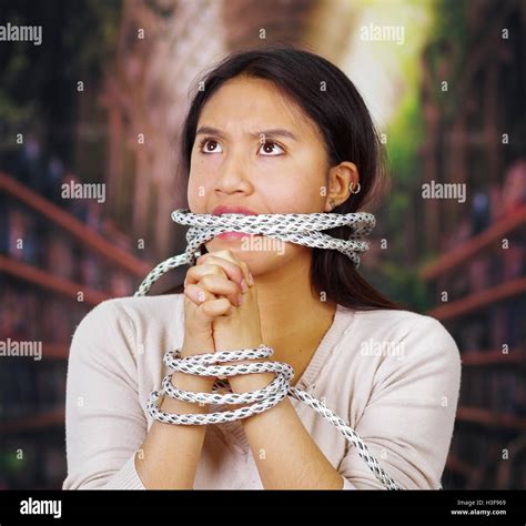 Young Brunette Woman Wearing White Sweater Tied Up With Rope Around Wrists And Gagged Mouth