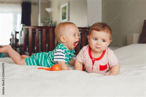 Group Portrait Of Two White Caucasian Cute Adorable Funny Baby Boys Lying Together On Bed