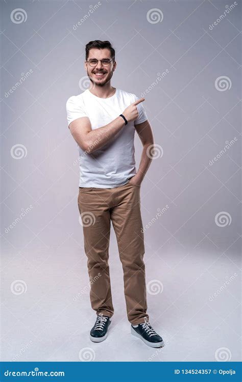 Smiling Young Casual Man Presenting Something On Gray Background Stock