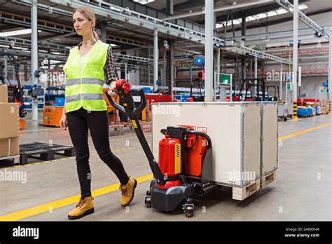 Warehouse Worker Dragging Hand Pallet Truck Or Manual Forklift With The Shipment Pallet
