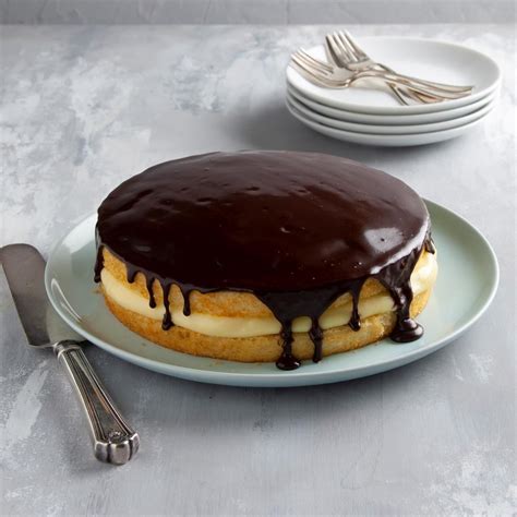 A Chocolate Covered Cake Sitting On Top Of A White Plate Next To Plates