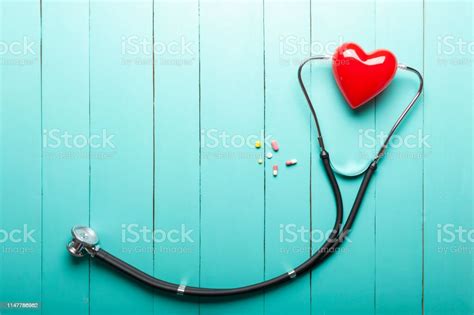 Top View Of Stethoscopes Red Heart Model And Drugs On Green Wooden Desk