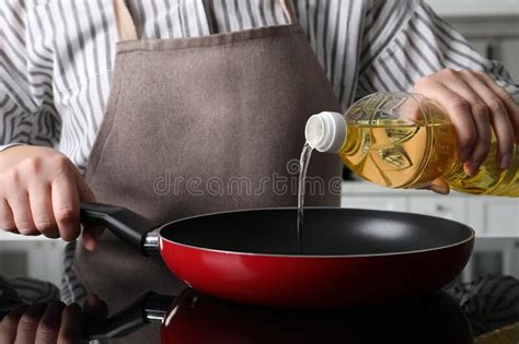 Woman Pouring Cooking Oil From Bottle Into Frying Pan On Stove Closeup