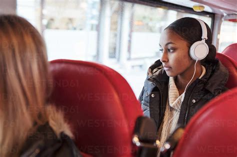 Thoughtful Teenage Girl Listening Music On Headphones While Looking Through Window In Bus Stock