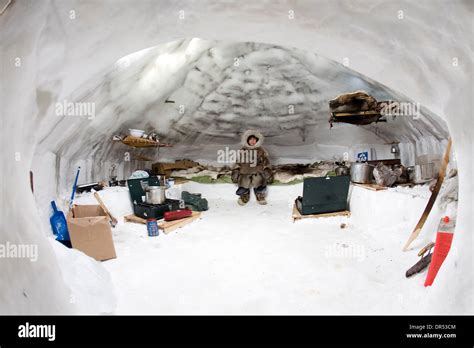 Un joven inuit se sienta en una cama en un iglú rodeado de otros elementos necesarios para