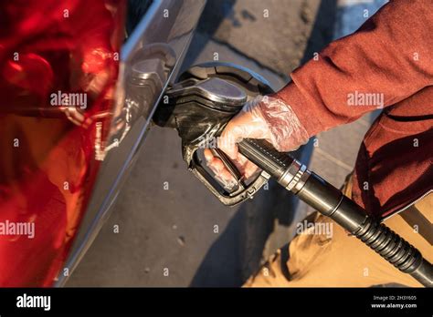 Close Up On Hand Of Unknown Caucasian Man Hold Black Gas Pump Nozzle