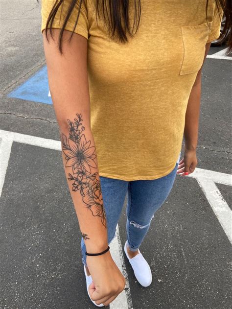A Woman With A Flower Tattoo On Her Left Arm And Right Leg Standing In