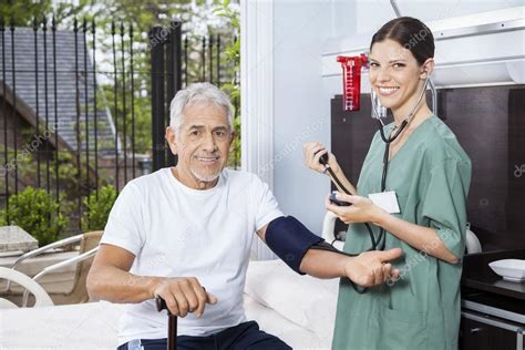 Senior Mans Blood Pressure Being Checked By Female Nurse Stock Photo By