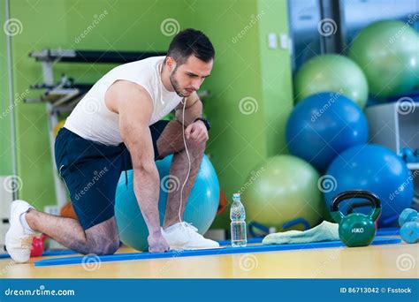 Male Athlete Kneeling Down By Dumbbells Toweling Sweat Of His Brow