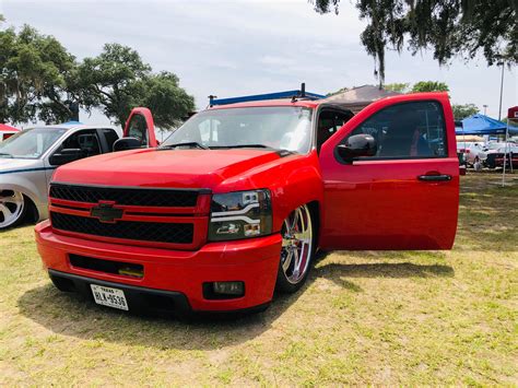 A Red Truck Parked In The Grass Next To Other Cars