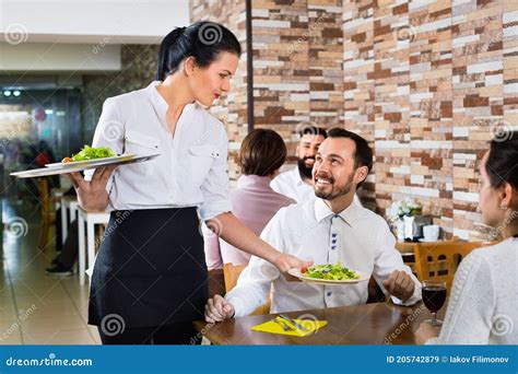 Female Waiter Bringing Order To Visitors In Country Restaurant Stock